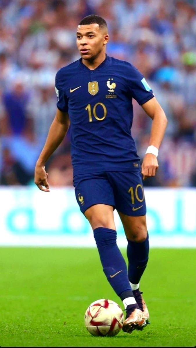 Ein männlicher Fußballspieler in einem blauen Trikot der französischen Nationalmannschaft mit der Rückennummer 10 dribbelt den Ball auf dem Stadionrasen. Der Hintergrund ist unscharf, im Hintergrund sind Fans auf den Tribünen zu sehen – ein Bild, das die Begeisterung einfängt, die Zuschauer oft erleben, wenn sie mit „IPTV Kaufen“ Live-Spiele streamen.